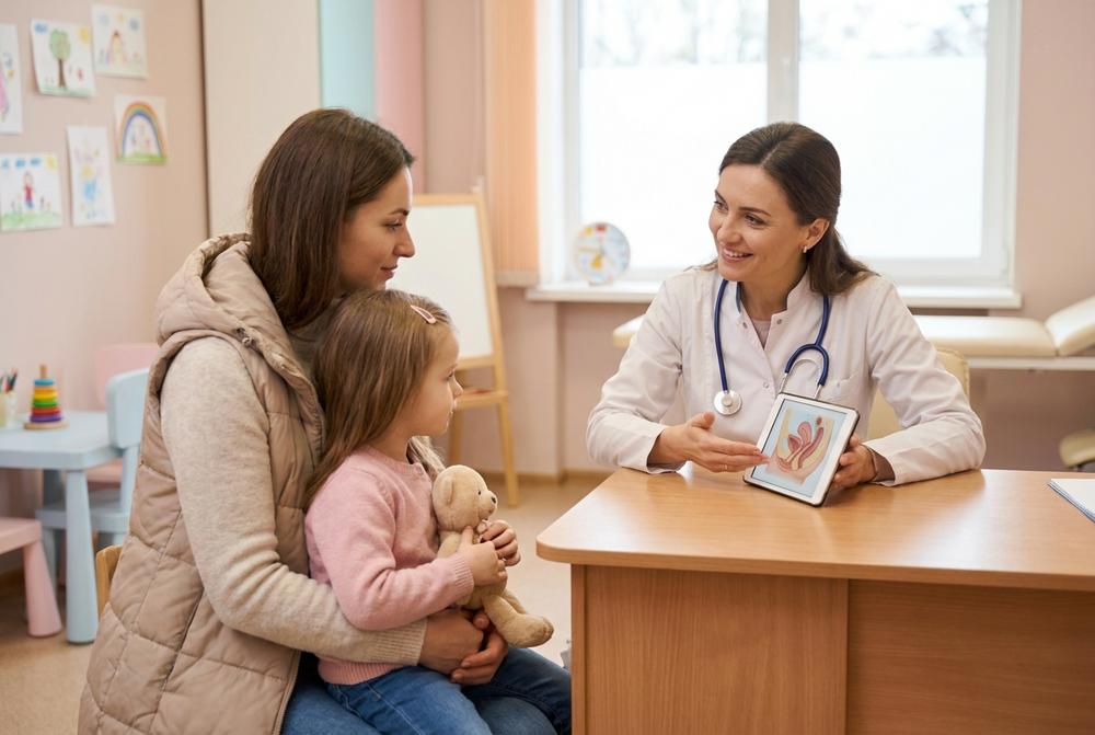 Pediatra bada dziecko w gabinecie, w tle dostępny ginekolog dziecięcy i konsultacje specjalistów dziecięcych