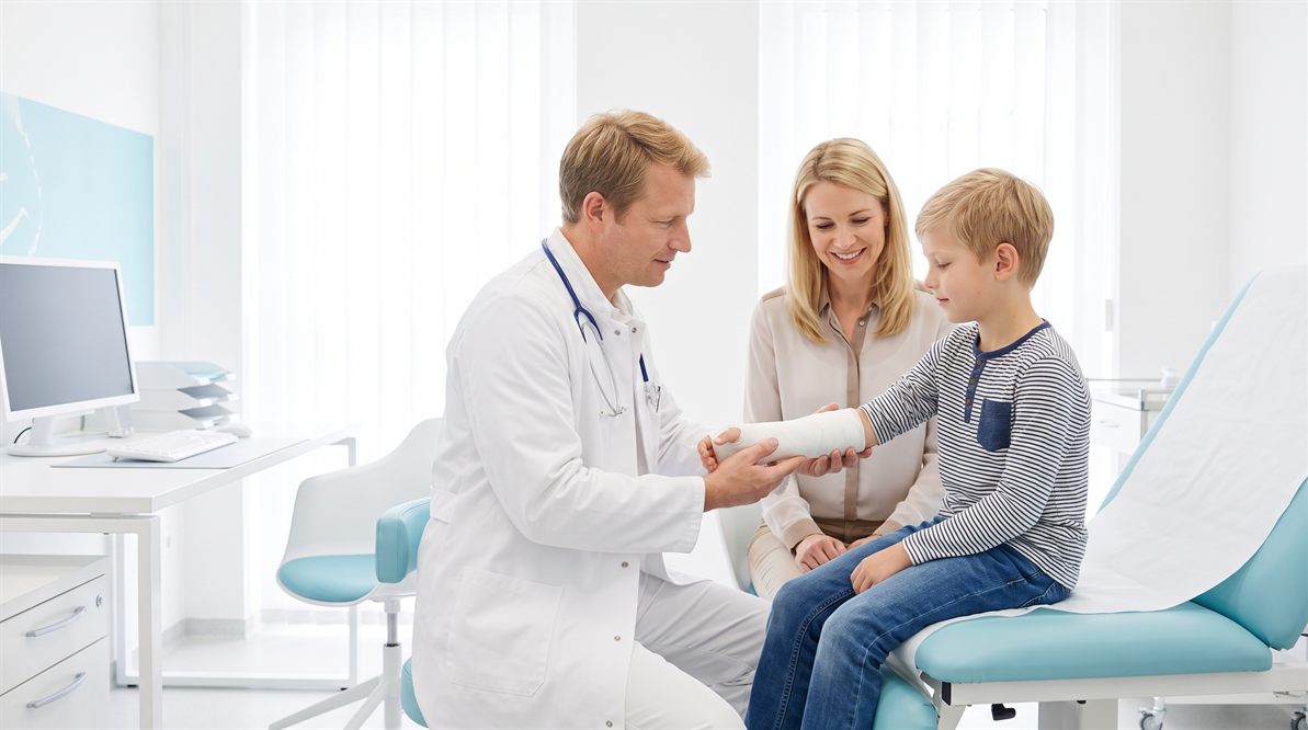 Ortopeda dziecięcy sprawdza gips na ręce chłopca podczas kontroli w Białymstoku